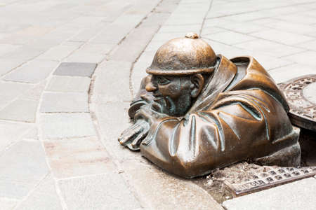 Cumil - statue of a man peeking out from under a manhole cover on May 9, 2013 in Bratislava,...
