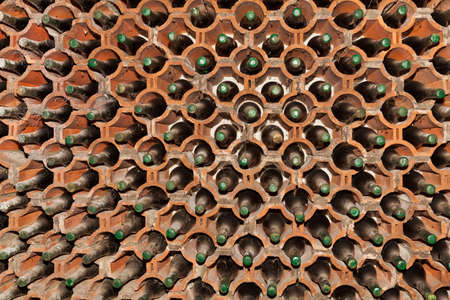 Archived glass bottles of wine in the shelf made of bricks in the wine cellar