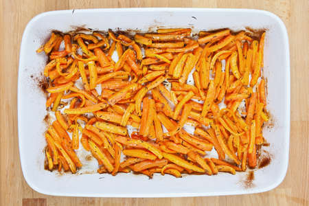 Peeled and sliced fresh organic carrots with olive oil, garlic and thyme roasted in a ceramic tray 