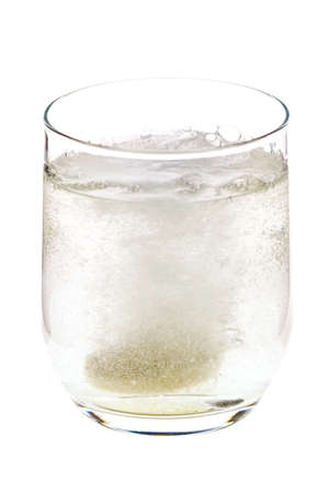 Fizzing pill tossed into the glass, dissolving and releasing bubbles, isolated on white backgroundの写真素材