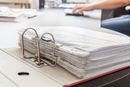 Open binder with papers in plastic wrapings on the desk by the man whoの写真素材