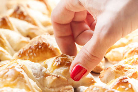 Closeup of a female hand reaching for freshly baked frankfurter sausages battered in puffed French pastryの写真素材