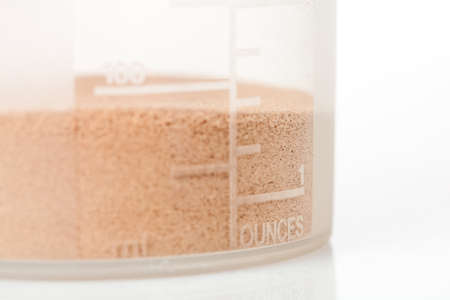 Chocolate whey isolate protein inside the shaker,with focus on the measuring scale, on white backgroundの写真素材