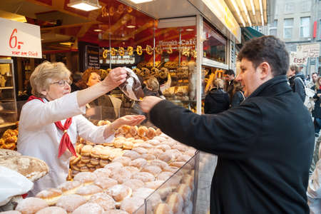 COLOGNE, GERMANY - MARCH 18, 2007: Woman selling pastry products and donuts on the streets of Cologne to a young man. Cologne is Germany's fourth-largest city and major cultural center of the Rhineland.のeditorial素材