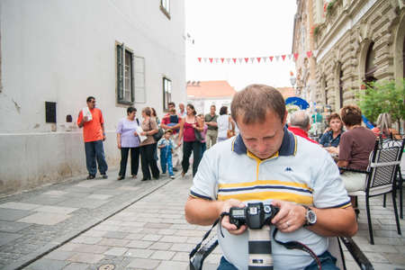 VARAZDIN, CROATIA - AUGUST 30, 2008: Photographer checking images on the camera on the terrace of the bar in a city street during Varazdin Spancirfest festival, a major cultural event held yearly in Varazdin.のeditorial素材