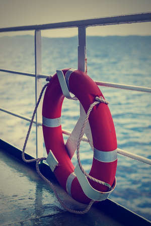Plastic orange saving belt by the railing fence of the ferry, against the Adriatic Sea;...