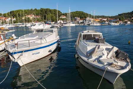 VELI IZ, CROATIA - AUGUST 17, 2014: Fishermen's boats parked and tied in city harbour in Veli Iz, on island Iz, with yacht in the marina in the background. Veli Iz is largest settlement on the island Iz.のeditorial素材