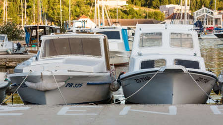 VELI IZ, CROATIA - AUGUST 15, 2014: Fishermen's boats parked and tied in city harbour in Veli Iz, on island Iz, with yacht in the marina in the background. Veli Iz is largest settlement on the island Iz.のeditorial素材