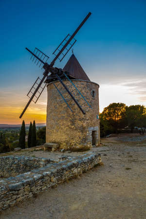 One of three old windmills on hill above the village Saint-Saturnin-les-Apt, France during sunsetの写真素材
