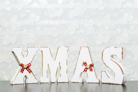White wooden letters on brown wooden table forming word XMAS with ribbons and buttonsの写真素材