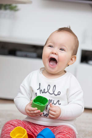 Nine months old baby girl playing with her toys on the floor
