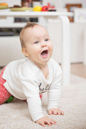 Nine months old baby girl playing with her toys on the floor and crawling Nine months old baby girl playing crawling on the floor carpetの写真素材