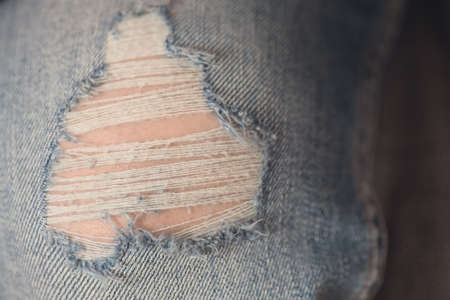 Closeup of a denim fabric pants; textile torn on the knees and threads coming apartの写真素材