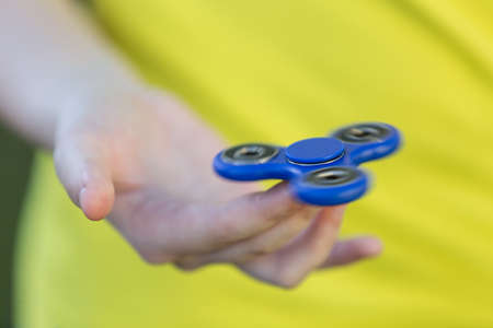 Girl's hand holding a spinning fidget spinner in her hand, spinning them on her index fingerの写真素材