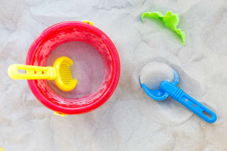 Plastic bucket, sifter and a small shovel in the sand; view from aboveの写真素材
