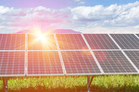 Panels of the solar energy plant under the blue sky with white clouds with sun flare hitting the surface - clean energy conceptの写真素材