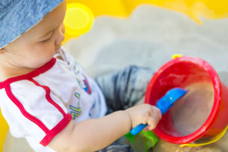 Fourteen months old baby girl playing with her colorful toys in the sand boxの写真素材