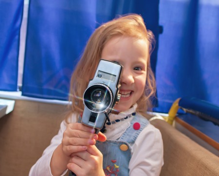 Portrait of a beautiful and confident small girl with camera. Little girl making a film in the...