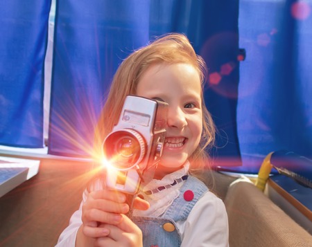 Portrait of a beautiful and confident small girl with camera. Little girl making a film in the...