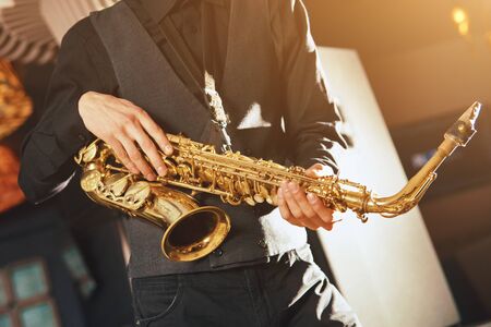 Young man in a suit hold a saxophone musical instrumentの写真素材