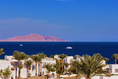 A beautiful view of the sea with pleasure boats and ships, the islands palm trees and the sun.の写真素材