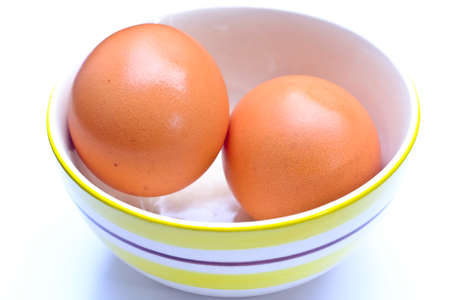 Two eggs in a cup placed on a white background.の写真素材