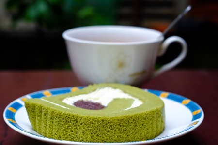 Green tea roll cake and hot cocoa on brown wooden table.の写真素材
