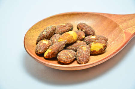 Almonds on wooden spoon, white background.の写真素材