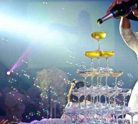 Just married couple pouring sparkling bubbly champagne into glasses. Selective focusの写真素材