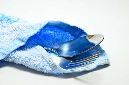 Spoon and fork wrapped in a napkin blue on white backgroundの写真素材