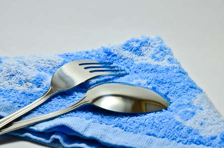 Spoon and fork wrapped in a napkin blue on white backgroundの写真素材