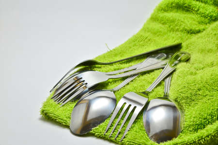 Spoon and fork wrapped in a napkin green on white backgroundの写真素材