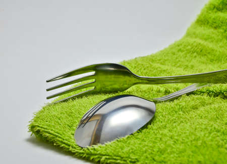 Spoon and fork wrapped in a napkin green on white backgroundの写真素材