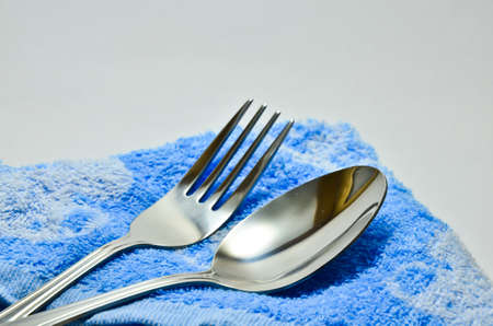 Spoon and fork wrapped in a napkin blue on white backgroundの写真素材