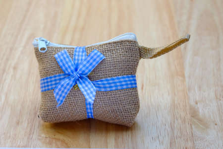 Bag hemp sack with blue ribbon on a wood background