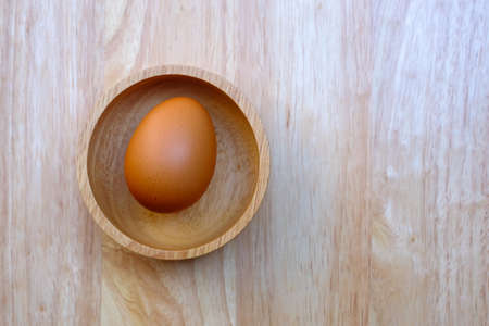 eggs in a wood cup on a wooden table.