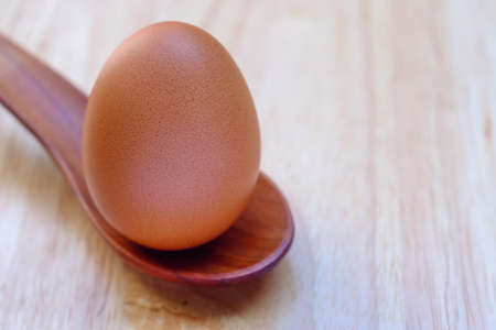 eggs in a wood spoon on a wooden table.の写真素材