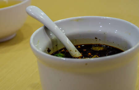 Chili sauce, dark soy sauce in a white cup.の写真素材
