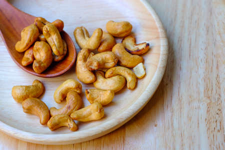 Cashew nuts and salt on a wooden plate on a wood table background.の写真素材