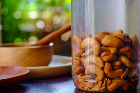 Cashew nuts and salt in a jar on a wooden table on a background bokeh.の写真素材