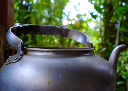 Boiling silver kettle with a wood stove on backgroundの写真素材