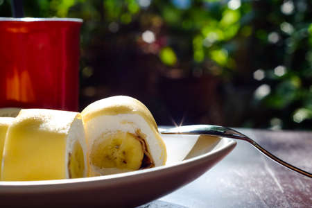 Crepes With banana and coffee red cup on wood table (Thai dessert)の写真素材