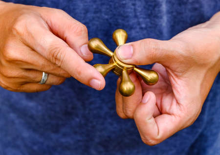 closeup of a young caucasian man playing with a brass fidget spinner.の写真素材