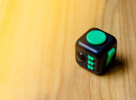 Fidget Cube stress reliever, fingers toy on wood background. An orange light shines. (relax)の写真素材