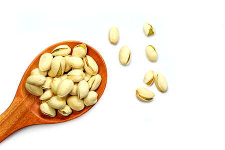Pistachio nuts in wooden spoon on white background, isolatedの写真素材
