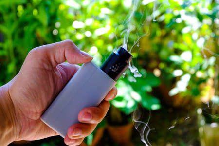 e-cigarette with hand close up on nature background