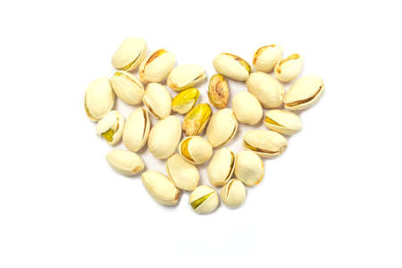 Pistachio nuts shape heart on white background, isolatedの写真素材
