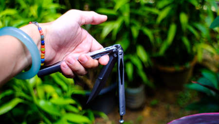 Butterfly knife (balisong) in female hand on a nature backgroundの写真素材