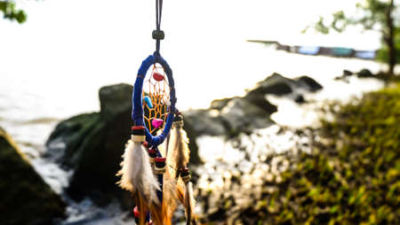 Dreamcather with sunset sea view background.,  Native american dream catcher. boho chic, ethnic amulet.の写真素材