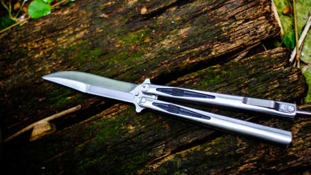 Butterfly knife (balisong) in a folded state against a old wooden floors backgroundの写真素材